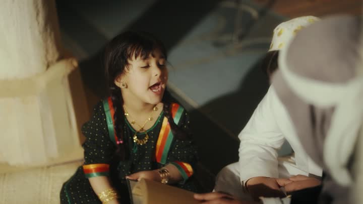 A story for the children, sitting in one of the traditional clay houses, on the day we began in 1727 AD, the love among family members, the anniversary of the founding of the first Saudi state on February 22, an Arab Gulf Saudi man sitting with his children wearing traditional costumes during national holidays.