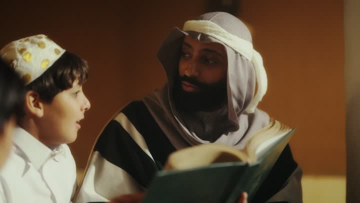 A story for the children, sitting in one of the traditional clay houses, on the day we began in 1727 AD, the love among family members, the anniversary of the founding of the first Saudi state on February 22, an Arab Gulf Saudi man sitting with his children wearing traditional costumes during national holidays.