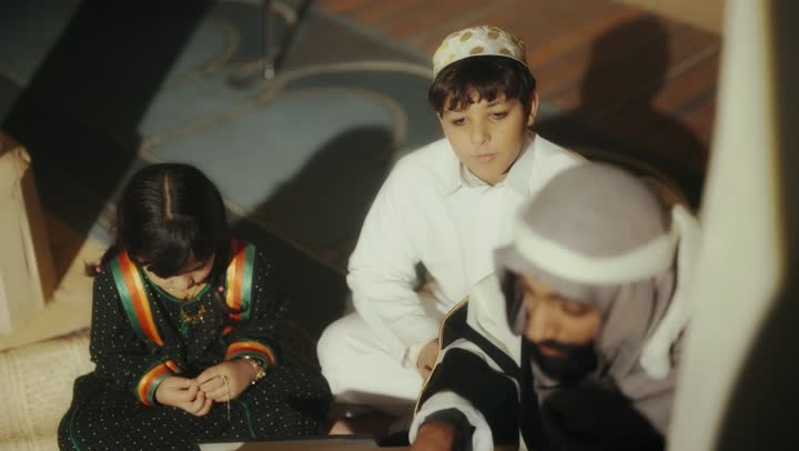 الجلوس في احدى البيوت التراثية الطينية ،يوم بدينا 1727 م ، رواية قصة للابناء، المحبة بين افراد الأسرة ،ذكرى تأسيس الدولة السعودية الأولى 22 فبراير ، رجل عربي خليجي سعودي يجلس مع أبنائه يرتدون الأزياء الشعبية في الأعياد الوطنية