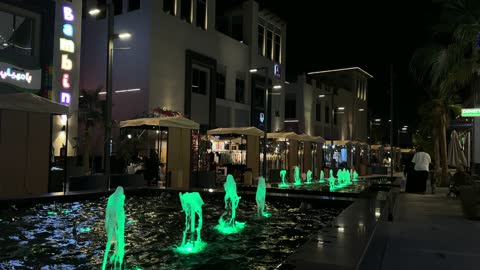 نافورة مضيئة في ساحة تجارية حديثة ليلاً