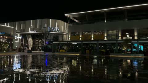 عرض النافورة المضيئة في ساحة تجارية حديثة ليلاً