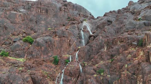 شلال يتدفق عبر المنحدرات الصخرية في الجبال الصحراوية