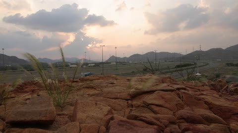 غروب الشمس فوق طريق سريع ومناظر جبلية صخرية