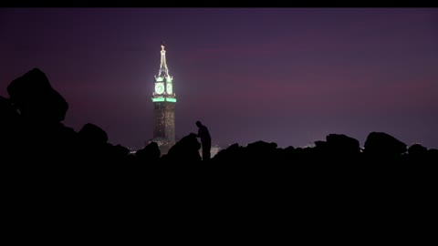 خيال رجل مع برج الساعة في مكة المكرمة ليلاً