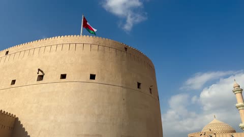 قلعة نزوى وعلم سلطنة عمان مع عمارة المسجد