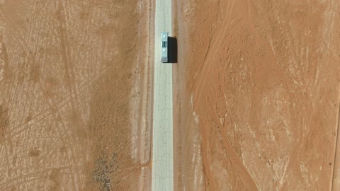 White Bus Driving on Desert Road Aerial Drone Footage