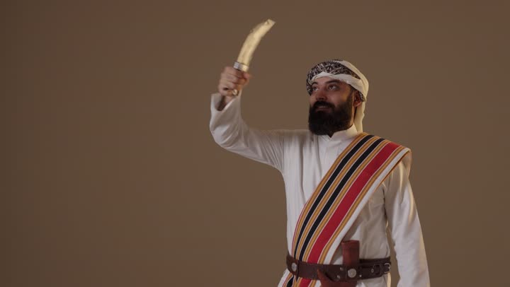 رجل سعودي بزي يوم التأسيس التقليدي يحمل خنجراً في الاستوديو