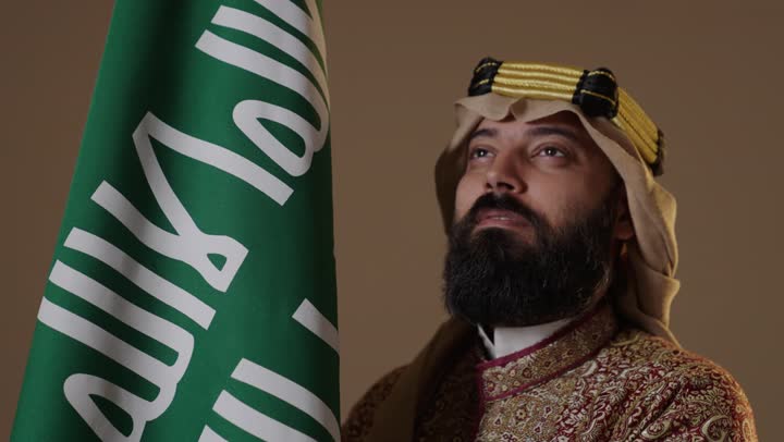 رجل سعودي بزي يوم التأسيس بجانب العلم