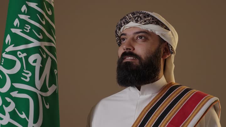 Saudi Man in Traditional Founding Day Attire with Flag