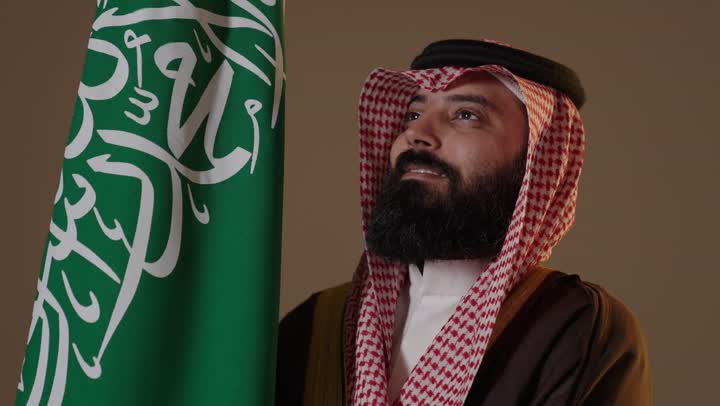 رجل سعودي بزي يوم التأسيس مع العلم الوطني