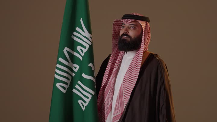 رجل سعودي بزي يوم التأسيس مع العلم الوطني