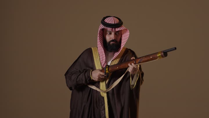 رجل سعودي بملابس يوم التأسيس يحمل بندقية قديمة