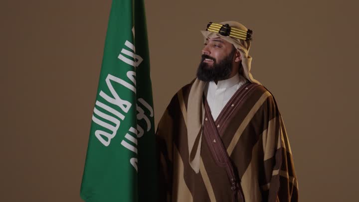 رجل سعودي مع العلم بملابس يوم التأسيس