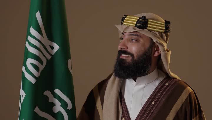 رجل سعودي بزي يوم التأسيس التقليدي مع العلم