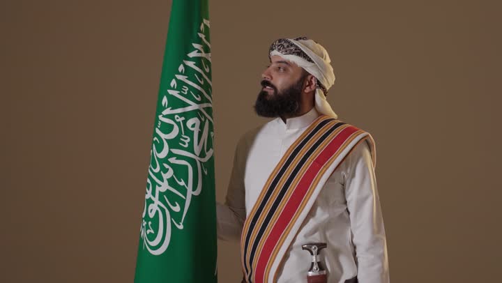 رجل سعودي بزي يوم التأسيس مع العلم الوطني