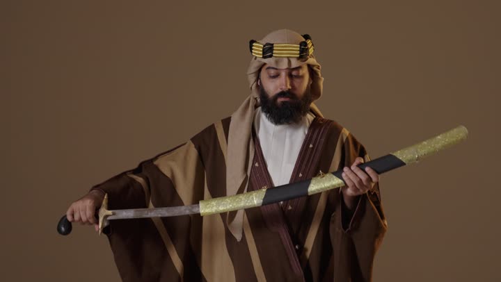 رجل سعودي بلباس يوم التأسيس التقليدي يحمل سيفاً