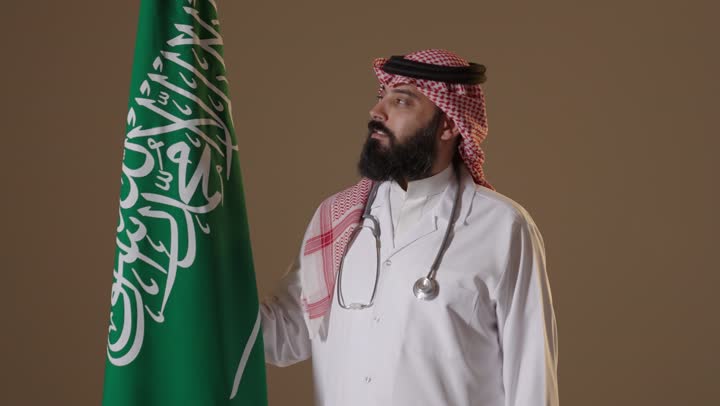 طبيب سعودي يقف مع العلم الوطني في استوديو احترافي