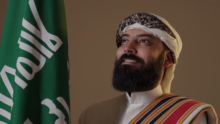 رجل سعودي بزي يوم التأسيس مع العلم الوطني