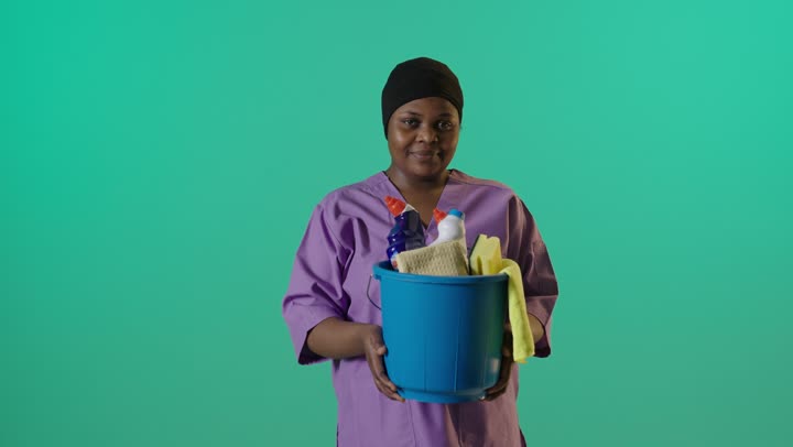 عاملة نظافة أفريقية تحمل دلو على كروما خضراء