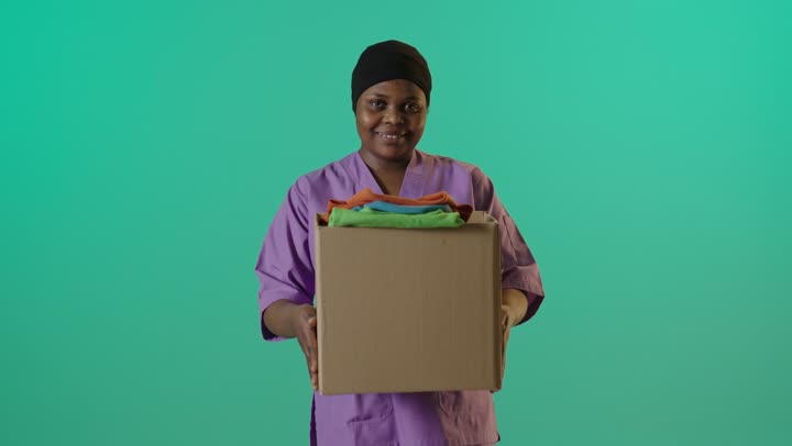ممرضة أفريقية تمسك صندوق تبرعات ملابس خلفية خضراء
