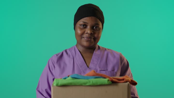 امرأة أفريقية تحمل صندوق ملابس خلفية خضراء