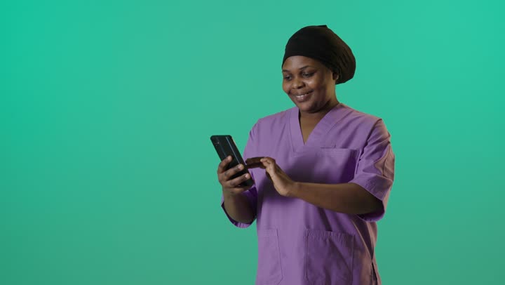 Black Female Nurse Using Smartphone on Green Screen
