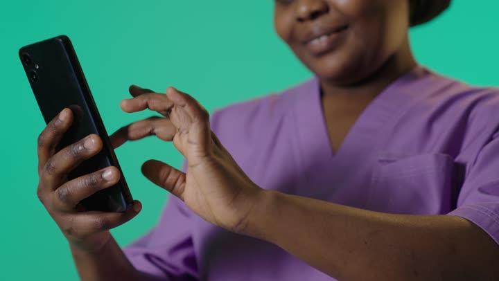 African Nurse Using Smartphone on Green Screen