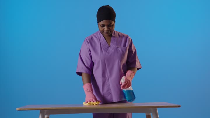 African Female Cleaner Wiping Table in Studio