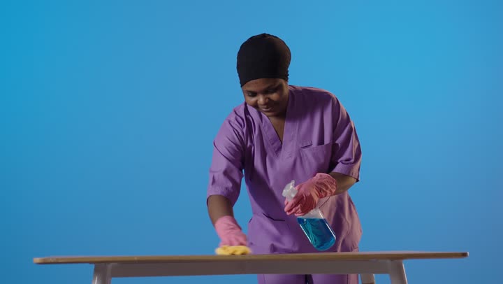 Black Female Professional Cleaner Wiping Table Studio Shot