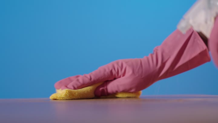 تنظيف سطح خشبي باستخدام قفازات وردية وبخاخ