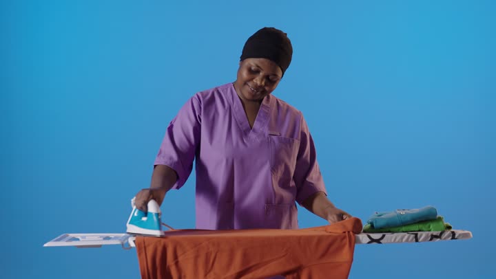 خادمة أفريقية تقوم بكي الملابس في الاستوديو