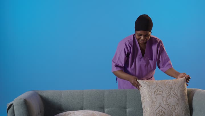 African Domestic Worker Arranging Sofa Pillows Studio