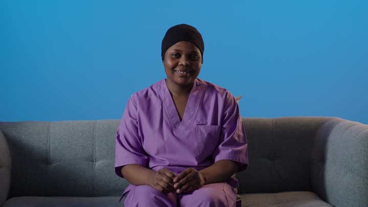 ممرضة سوداء ترفع إبهامها أمام خلفية زرقاء