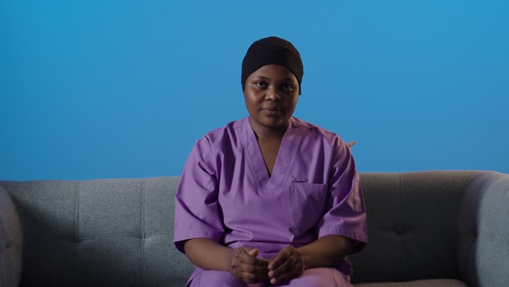 ممرضة سمراء تشير بالتوقف خلفية زرقاء