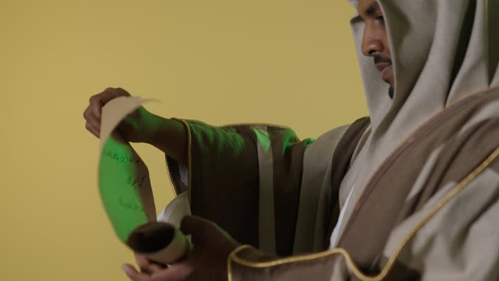 رجل سعودي باللباس التقليدي يقرأ وثيقة تاريخية قديمة