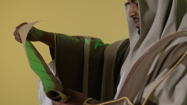 رجل سعودي بلباس يوم التأسيس يقرأ مخطوطة