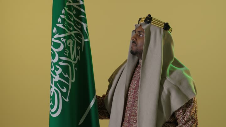 رجل سعودي بزي يوم التأسيس التقليدي مع العلم