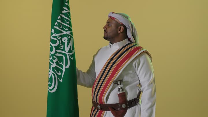 رجل سعودي بزي يوم التأسيس مع العلم الوطني