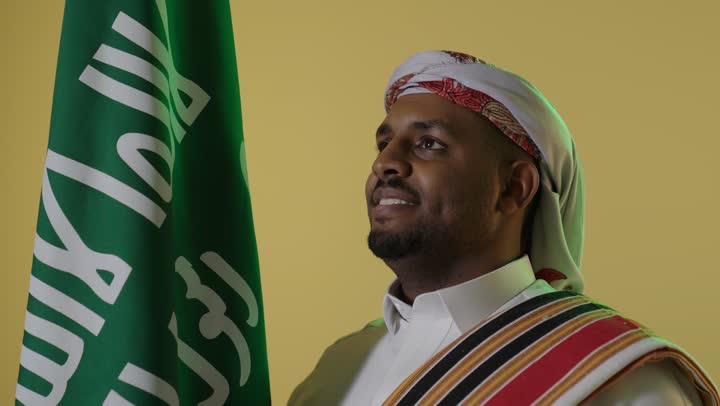 Saudi Man in Traditional Founding Day Attire with Flag