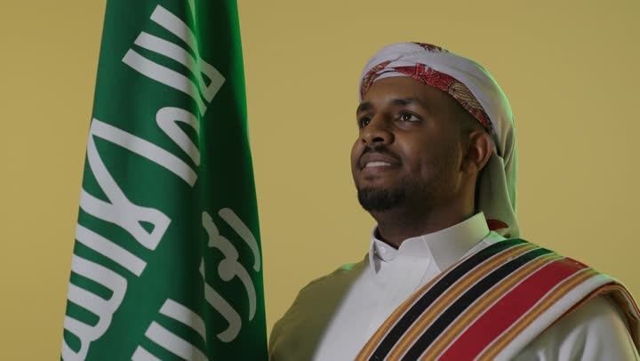 Saudi Man in Traditional Founding Day Attire with Flag
