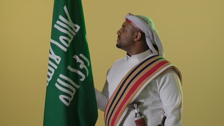 رجل سعودي بزي يوم التأسيس مع العلم الوطني