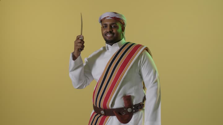 رجل سعودي بملابس يوم التأسيس التقليدية يحمل خنجراً