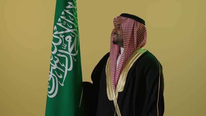 رجل سعودي بالبشت التقليدي مع العلم الوطني