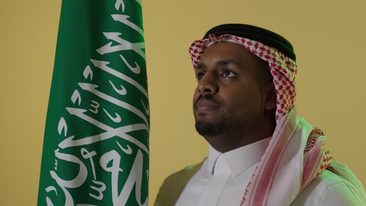 Saudi Man in Traditional Dress with Kingdom Flag