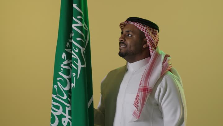 رجل سعودي مع العلم الوطني في يوم التأسيس