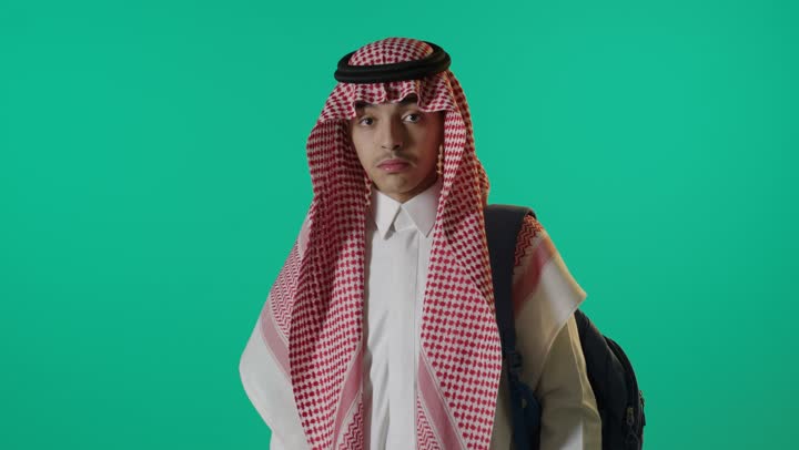شاب سعودي يشير بالإبهام للأعلى أمام خلفية خضراء