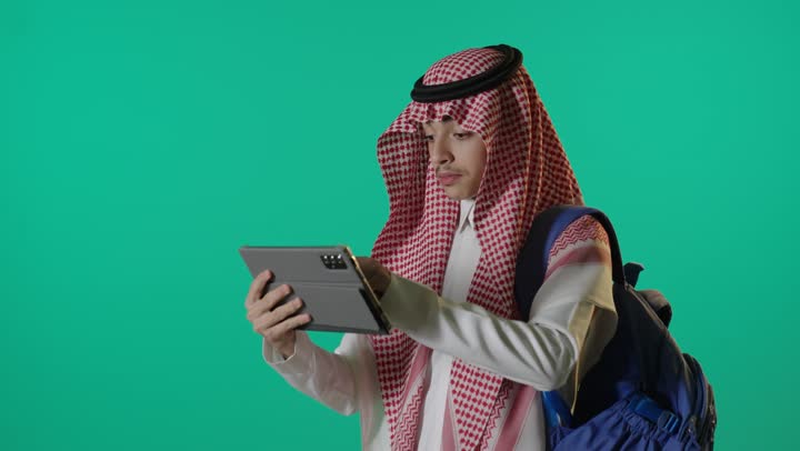 طالب سعودي يستخدم الجهاز اللوحي على خلفية خضراء