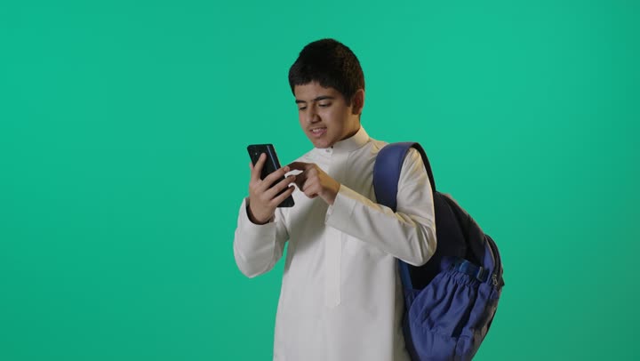طالب سعودي يستخدم الهاتف الذكي بخلفية خضراء