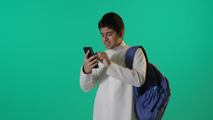 طالب سعودي يستخدم الهاتف الذكي أمام كروما خضراء