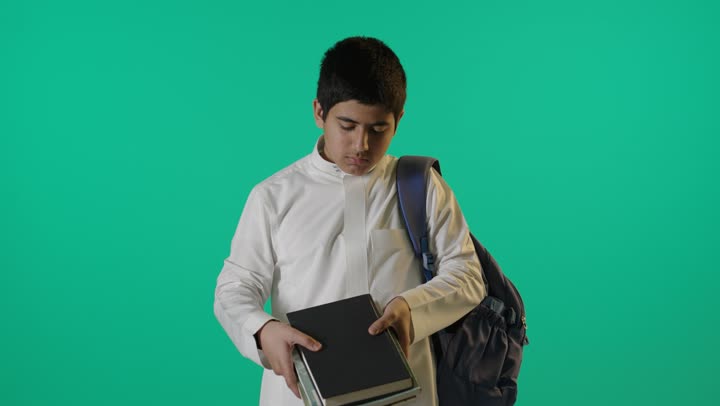 طالب سعودي يحمل كتب مدرسية كروما خضراء
